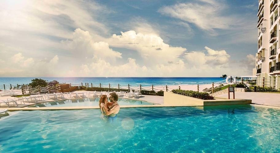 Pareja en piscina de dos niveles con vistas al mar de Park Royal Grand Cancún