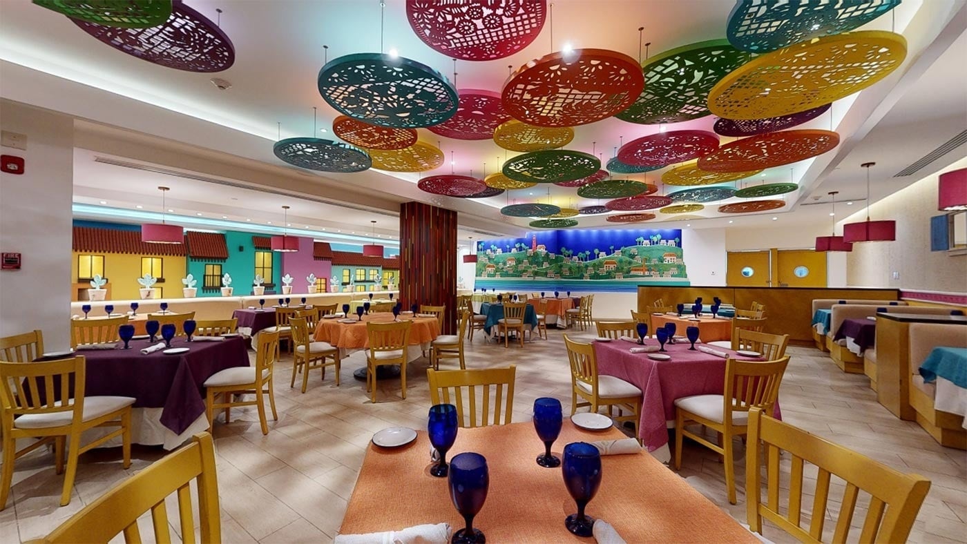 Comedor colorido del Hotel Park Royal Beach Cancún con mesas vestidas para cenar en el Caribe Mexicano.