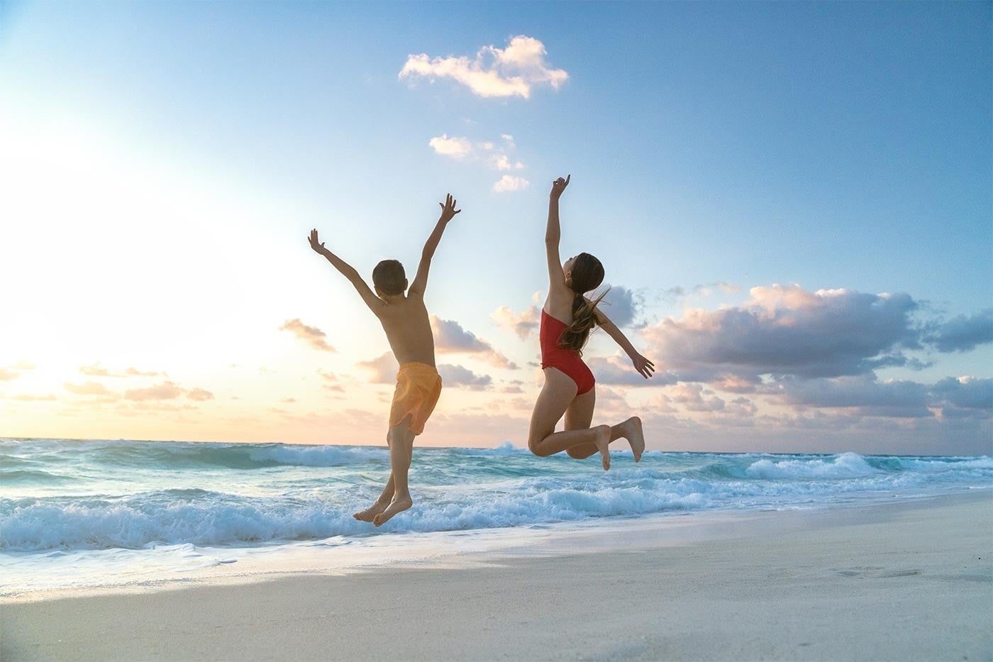 Hotel Grand Park Royal Cancun: Kids jump joyfully on a stunning Mexican Caribbean beach at sunset.
