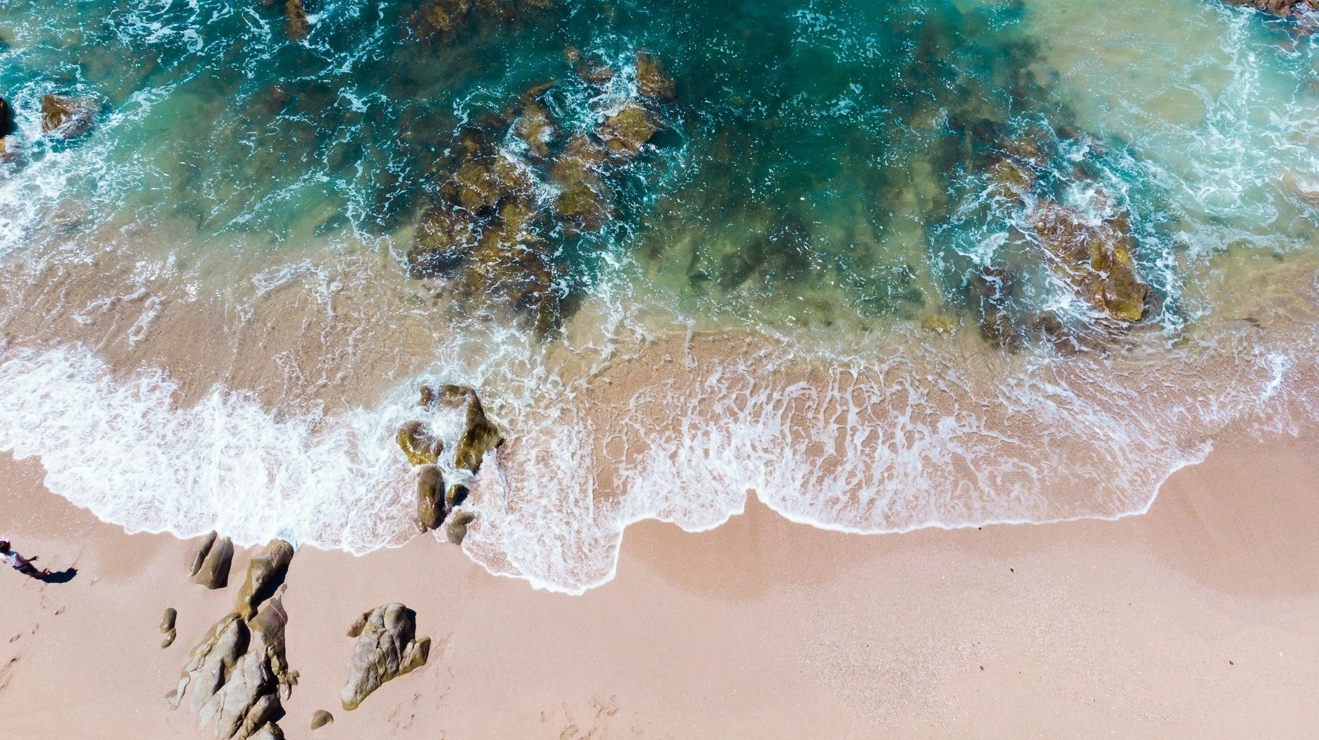 una vista aérea de una playa con olas y rocas