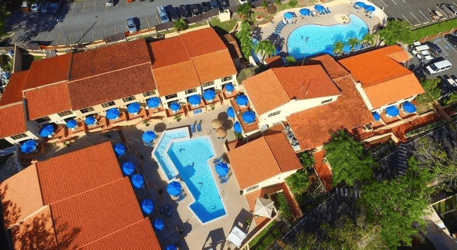 una vista aérea de un complejo de apartamentos con piscinas y sombrillas