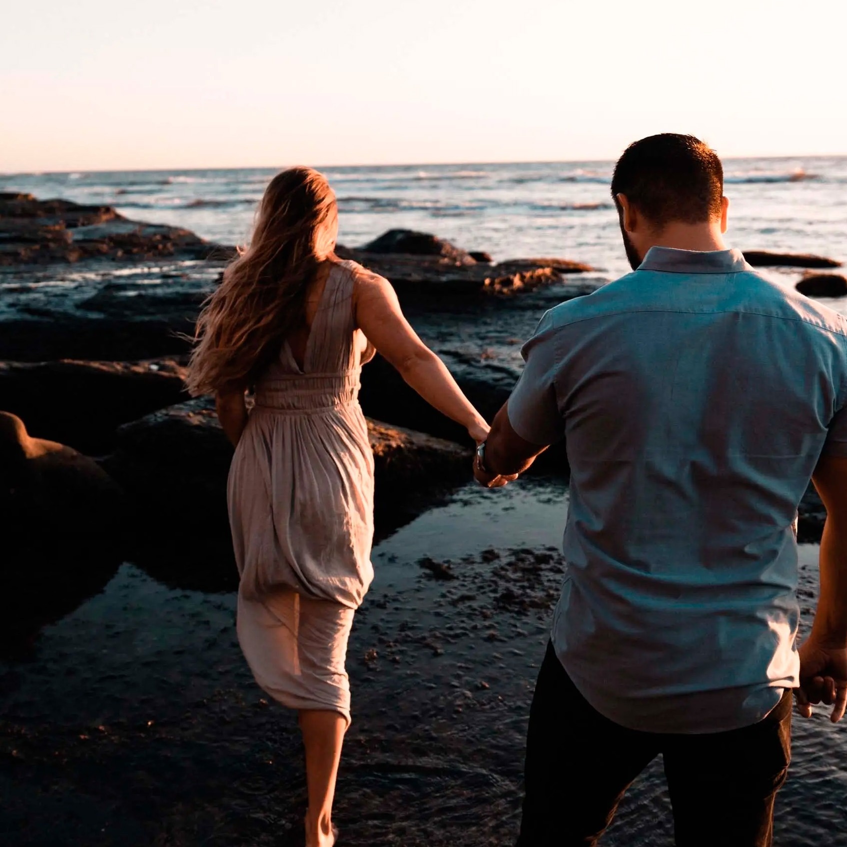 Pareja en Park Royal: Club Regina Los Cabos, caminando en la playa al atardecer.