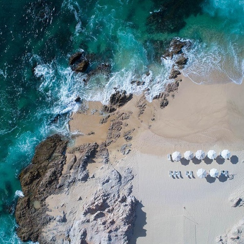 Vista aérea de playa con sombrillas y camastros en Park Royal: Club Regina Los Cabos.