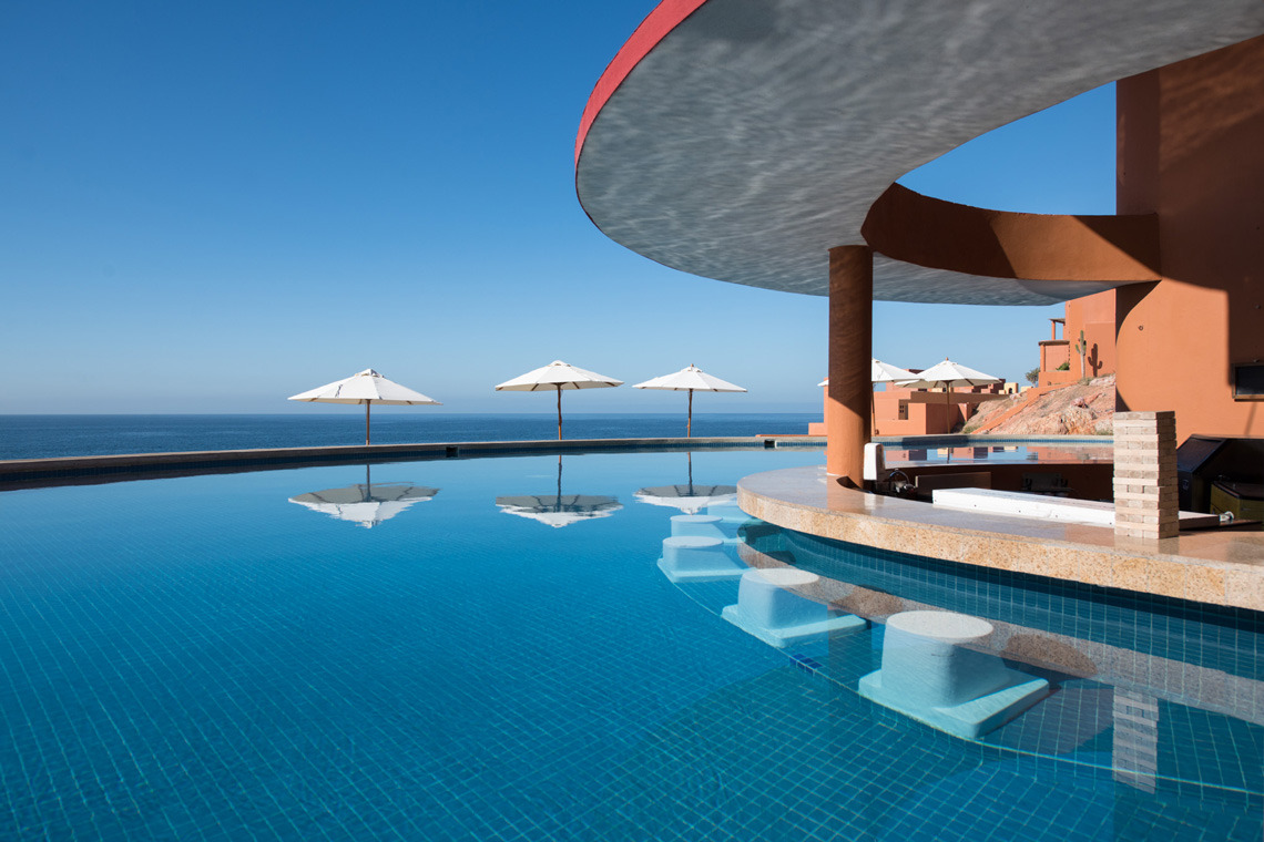 Bar de piscina y sillones a rayas en Park Royal: Club Regina Los Cabos.