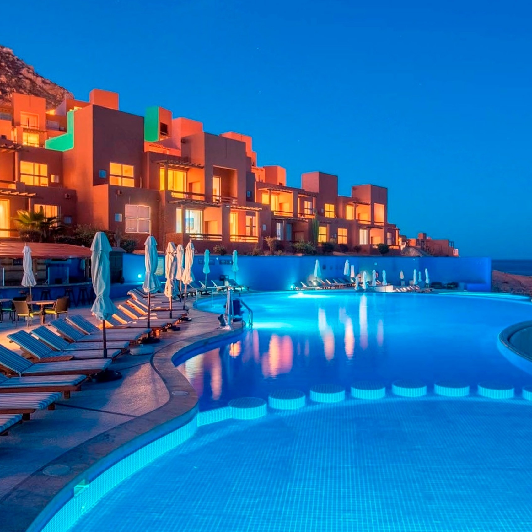 Piscina iluminada y resort del Park Royal: Club Regina Los Cabos al anochecer.