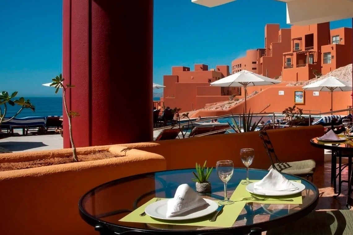 Terraza de restaurante con vista al mar en Park Royal: Club Regina Los Cabos, mesas puestas.