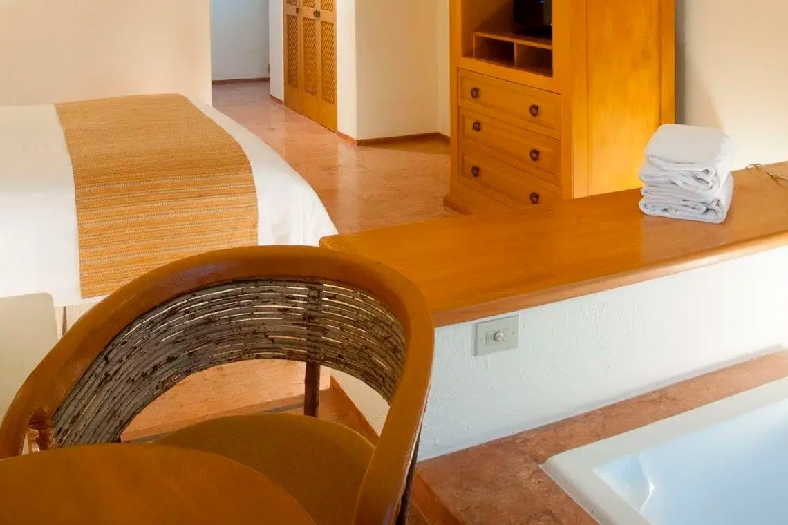 Habitación de lujo en Park Royal: Club Regina Los Cabos con cama cómoda y tocador.