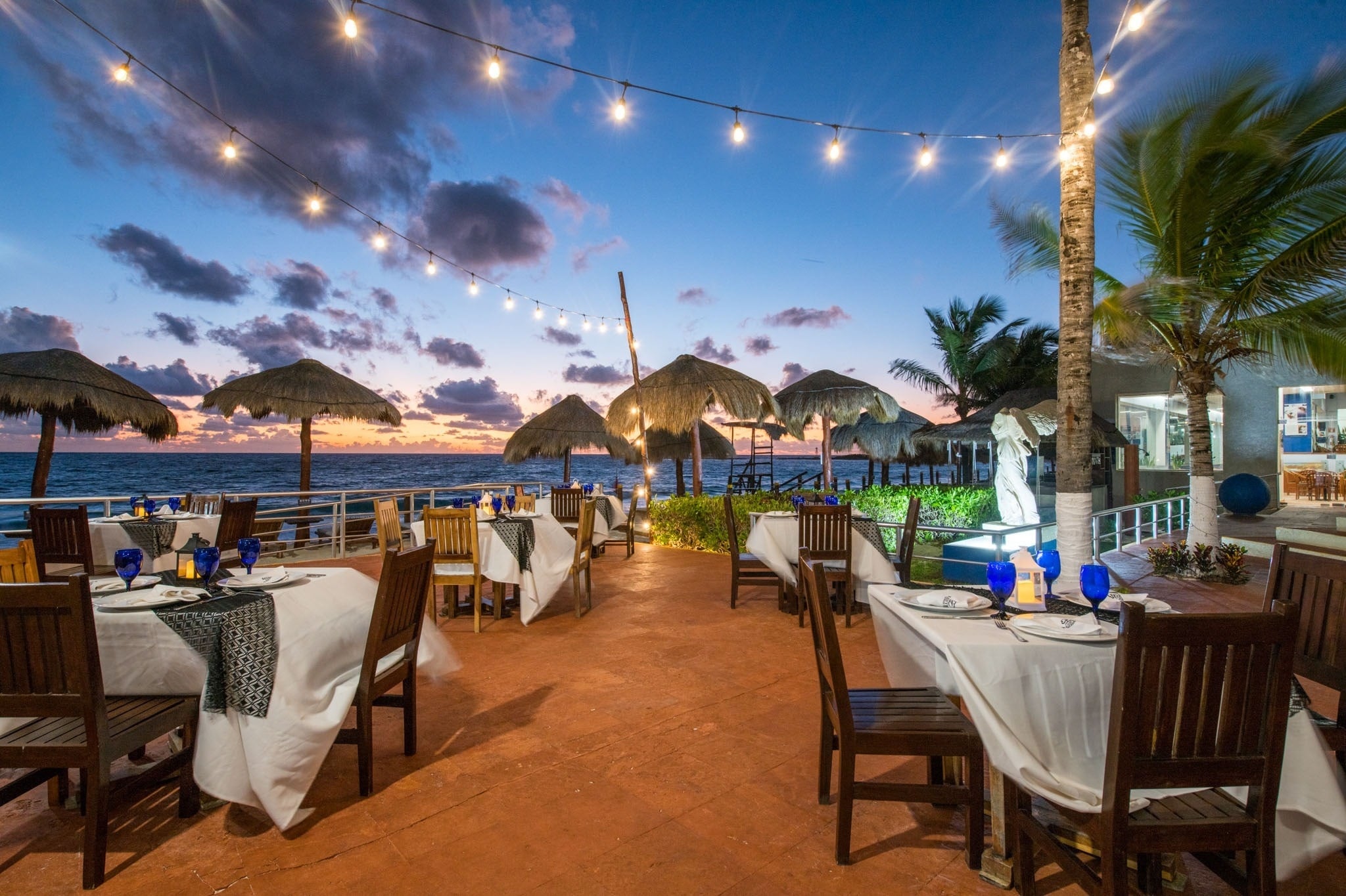 Terraza con mesas y sillas en Park Royal: Club Regina Cancun, al atardecer.