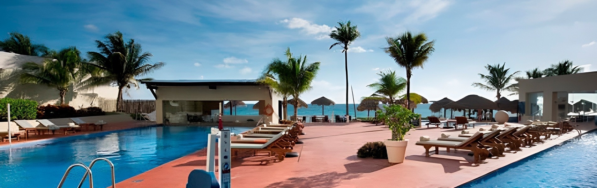 Sunny resort pool with lounge chairs and palm trees. Location | Hotel Roger de Flor | Lloret de Mar | Official Website