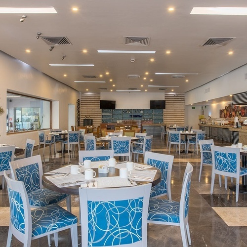 Restaurante elegante en Park Royal: Club Regina Cancún con mesas y sillas azules.