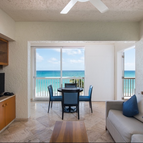 Sala de estar con vista al mar en Park Royal Club Regina Cancun, con mesa de comedor y sofá.