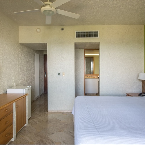 Habitación de hotel en Park Royal: Club Regina Cancún con cama king, TV y entrada a baño.