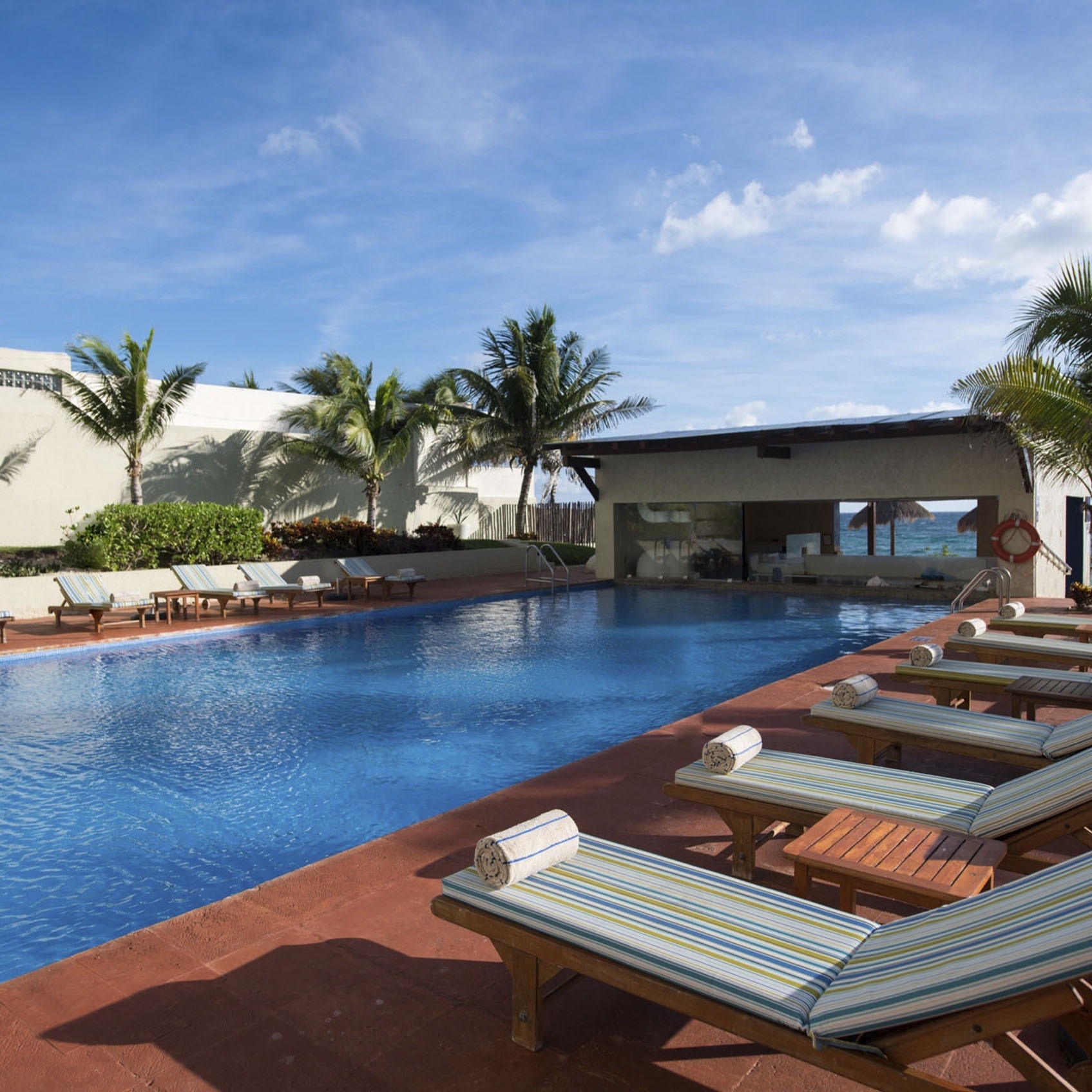 Park Royal: Club Regina Cancun. Lounge chairs by blue pool, palm trees, and ocean view.