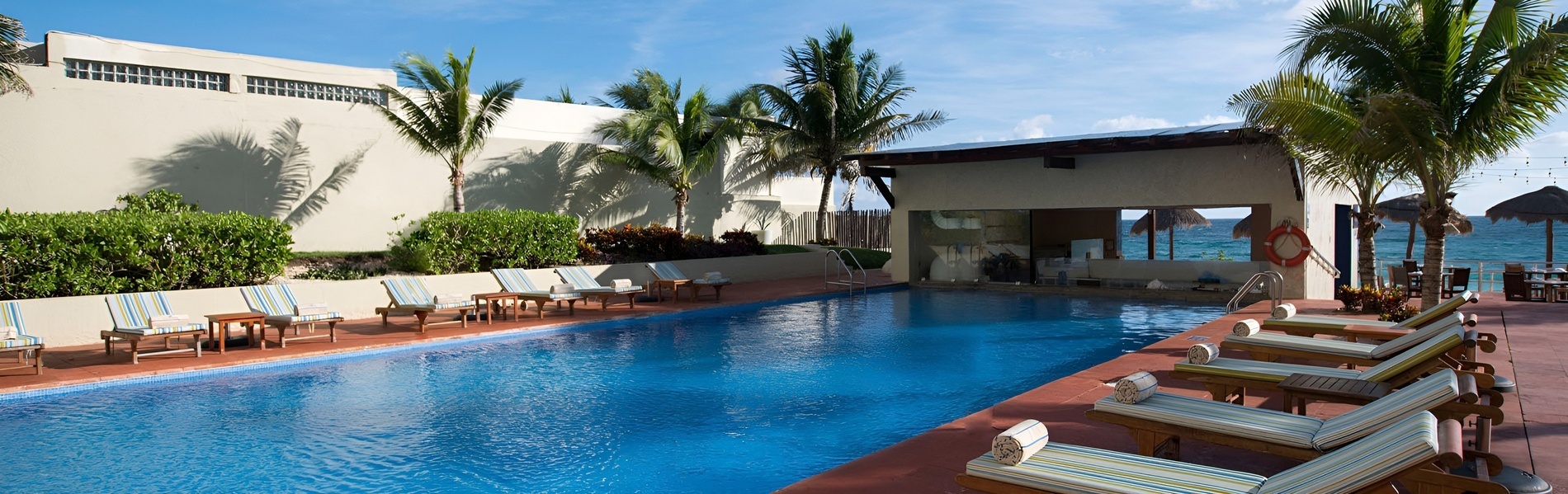 Piscina del hotel Park Royal: Club Regina Cancún con tumbonas y vista al mar.