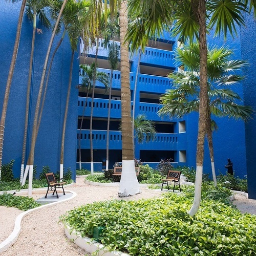 Patio azul vibrante en Park Royal: Club Regina Cancún con palmeras y asientos.
