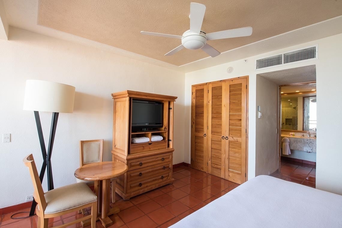 Habitación de hotel en Park Royal: Club Regina Puerto Vallarta con TV, armario de madera y baño.