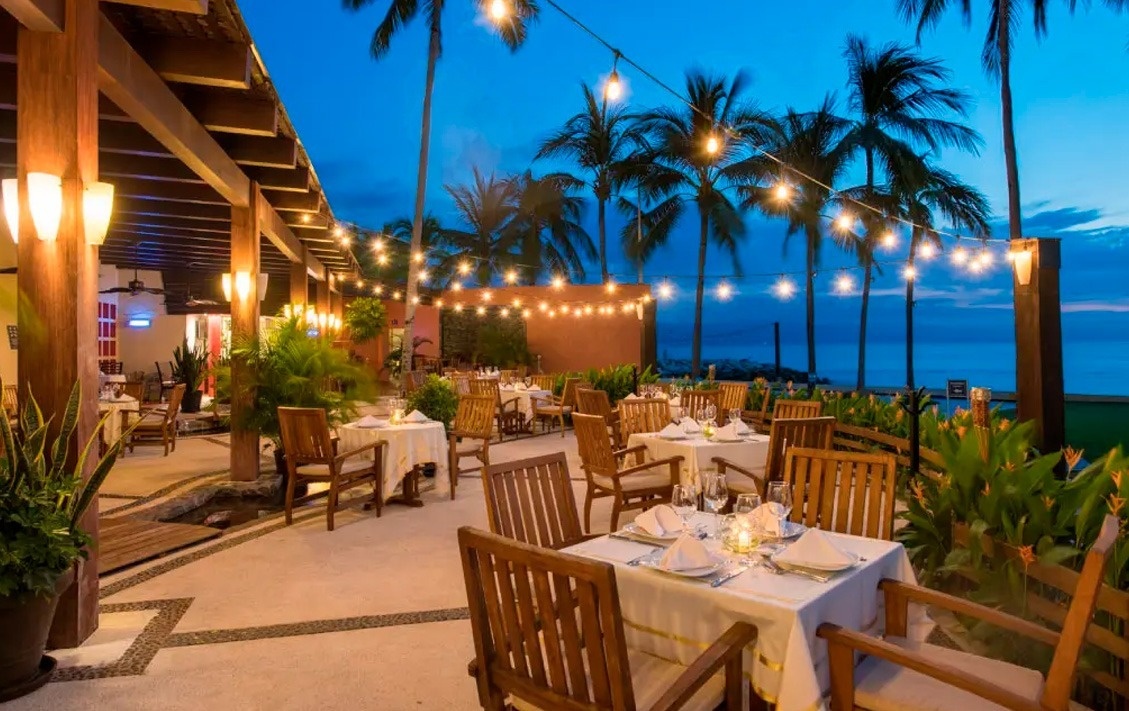 Restaurante al aire libre con mesas, sillas y luces en Park Royal: Club Regina Puerto Vallarta.