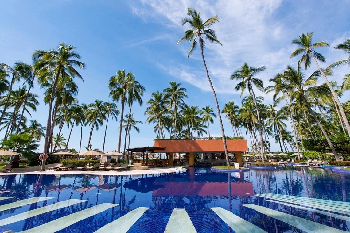 Piscina en Park Royal: Club Regina Puerto Vallarta, rodeada de palmeras y con tumbonas.