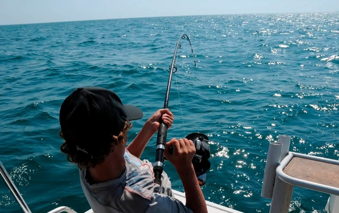 Niño pescando desde un barco, disfrute de la pesca en Park Royal: Club Regina Puerto Vallarta.