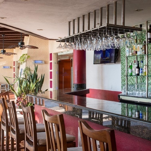 Bar de piscina en Park Royal: Club Regina Puerto Vallarta. Botellas y copas en exhibición.