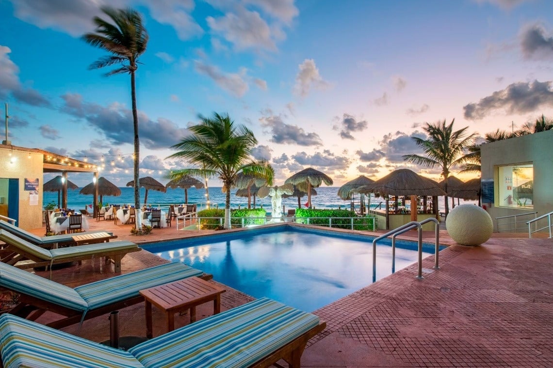 Piscina en Park Royal: Club Regina Puerto Vallarta al atardecer, con playa y palmeras.