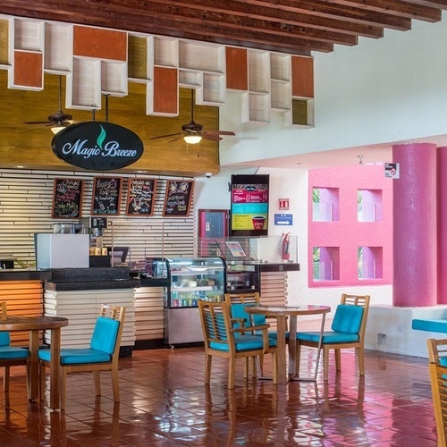 Cafetería vibrante en Park Royal: Club Regina Puerto Vallarta con mesas y sillas azules.