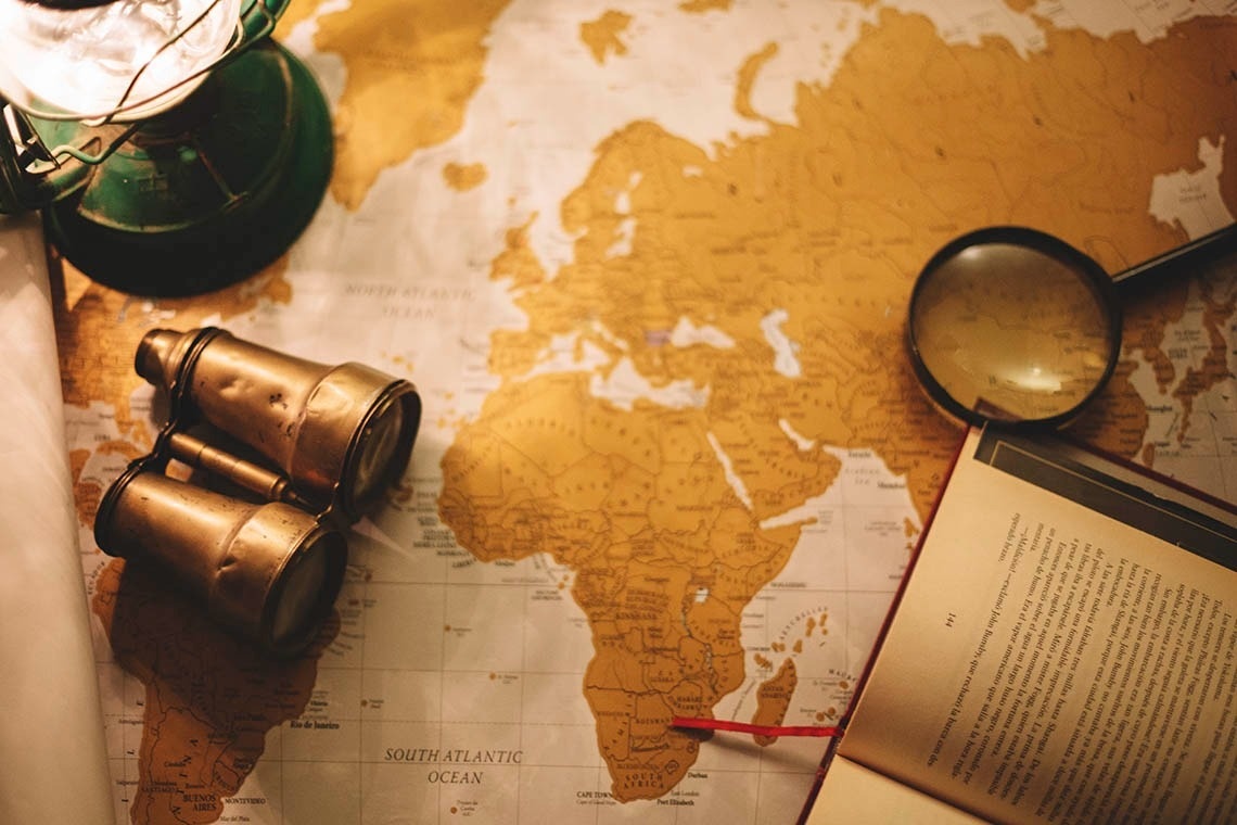 Vintage map, binoculars, and book, perfect for Pato Corporativa's strategic travel planning.