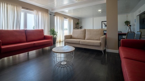 Pato Rojo Hotel lounge with inviting red & beige sofas, dark wood floor, and bright windows in Punta Umbria.