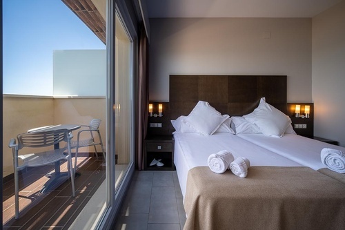 Cozy hotel room with balcony and comfortable bed at Hotel Pato Amarillo, a 4-star hotel in Punta Umbría.