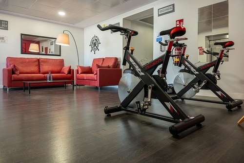 Pato Rojo Hotel in Punta Umbria (Huelva) lounge & gym space with red sofas and stationary bikes.