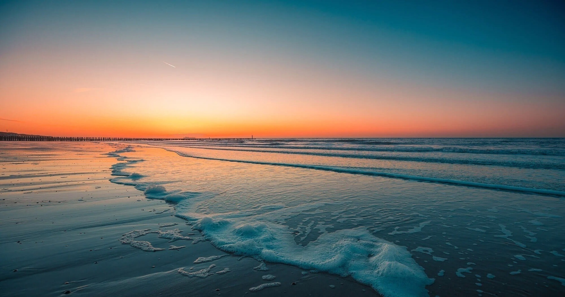 Pôr do sol na praia com ondas e céu alaranjado. Descubra o que ver em Punta Umbría | Arredores | Hoteles Pato.