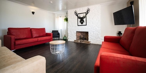 Modern lounge at Pato Rojo Hotel in Punta Umbria: red sofas, fireplace, TV, deer decor.