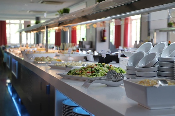 Bright hotel buffet line with fresh salads, various dishes, and bowls, ready for Pato: Corporativa guests.
