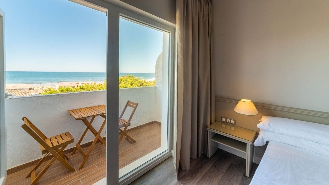 Cómoda habitación de hotel con balcón privado, vistas al mar y la playa. Perfecta para viajes Pato: Corporativa.