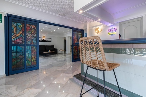 Lobby of Pato Rojo Hotel in Punta Umbria, Huelva, with stained-glass doors, marble floors, and a bar.