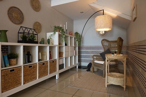 Cozy hotel lounge with wicker furniture, shelving, and plants at Hotel Pato Amarillo | 4-star hotel in Punta Umbría (Huelva).