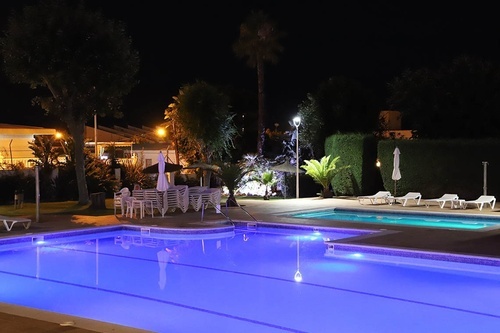 Hotel Pato Amarillo night scene: illuminated pools, gardens & seating at our 4-star hotel in Punta Umbría.