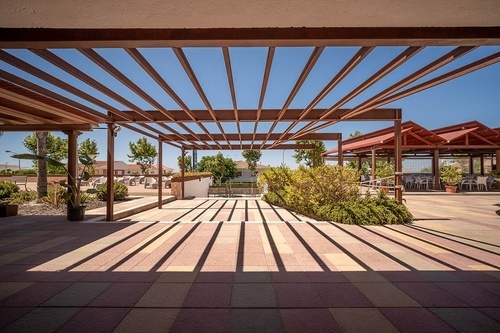 Pato Rojo Hotel's inviting outdoor patio with pergola shadows, perfect for relaxation in Punta Umbria.