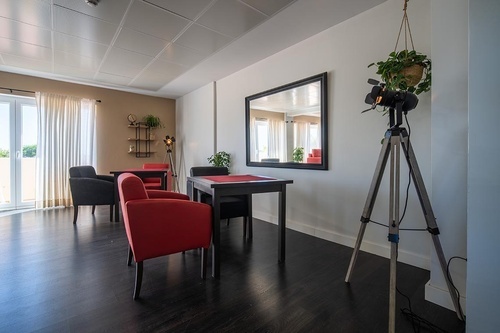 Pato Rojo Hotel in Punta Umbria: Cozy lounge with red and gray chairs, dark tables, and elegant decor.