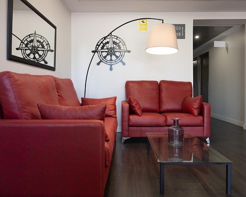 Pato Rojo Hotel lounge with comfortable red leather sofas, modern lamp, and nautical wall decor.