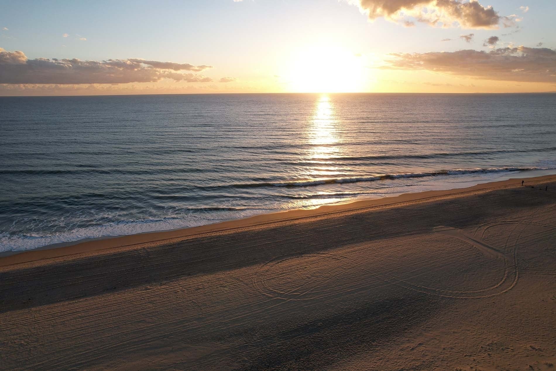 Amanecer dorado sobre el mar y playa, olas suaves. Ideal para Pato: Corporativa.