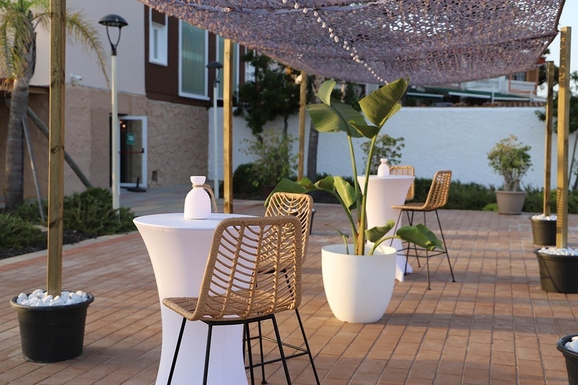 Terraza exterior de hotel con mesas altas y sillas, ambiente perfecto para eventos Pato: Corporativa.