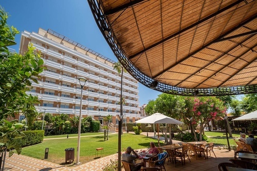 Hotel Pato Amarillo, 4-star hotel in Punta Umbría, Huelva. Outdoor dining and lush garden with hotel view.
