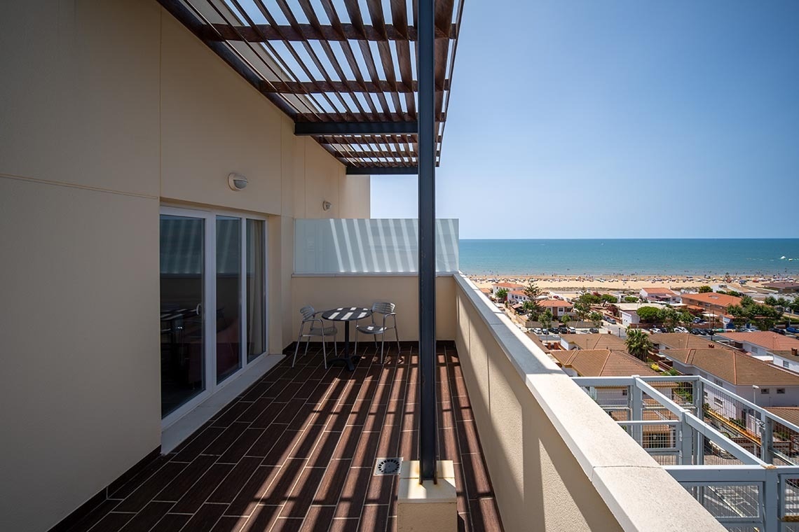 Pato: Corporativa hotel balcony offering panoramic sea, beach, and town views with outdoor dining.
