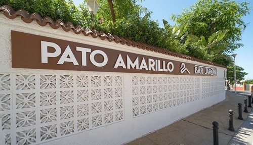 Hotel Pato Amarillo, a 4-star hotel in Punta Umbría, Huelva. Entrance sign with decorative wall & garden bar.