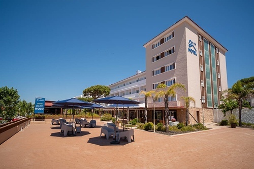 Pato Rojo Hotel in Punta Umbria, Huelva. Modern hotel exterior with outdoor seating and palm trees under a clear sky.