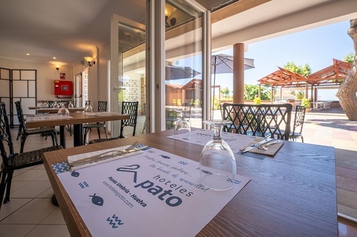 Restaurant at Pato Hotel Punta Umbría, Huelva, with indoor seating and outdoor patio dining under sunny skies.