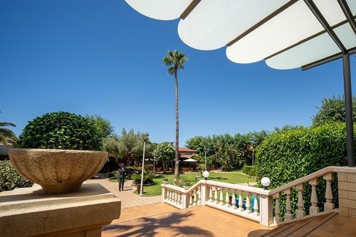 Sunny garden view with palm tree and elegant patio at Hotel Pato Amarillo, 4-star hotel in Punta Umbría, Huelva.