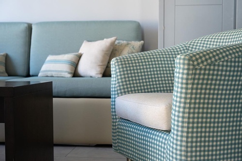Cozy seating area with blue couch and gingham armchair at Hotel Pato Amarillo, 4-star hotel in Punta Umbría, Huelva.