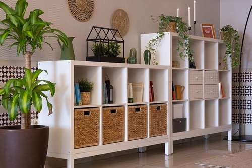 Hotel Pato Amarillo offers a warm common area with white shelving, lush plants, books & storage baskets.